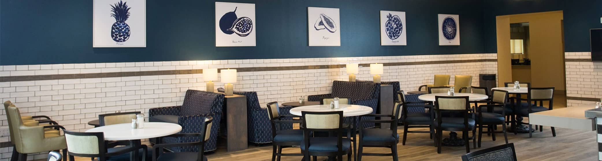 Interior of Emerald Court gathering area, with tables and chairs with a blue wall background.